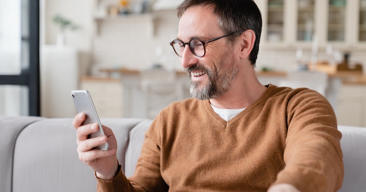 A patient at home reading a message on his phone