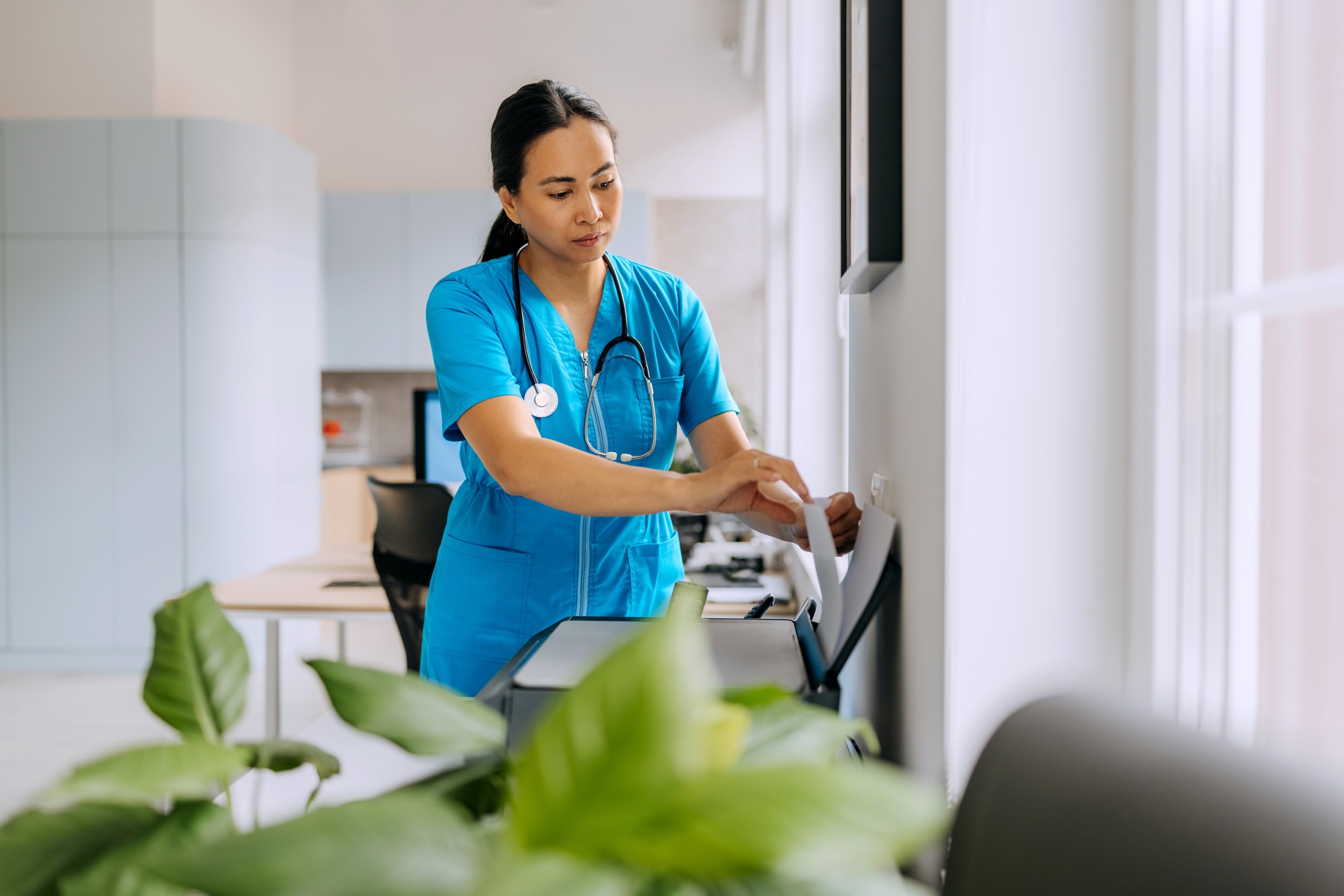 Nurse collecting pages from an office fax machine